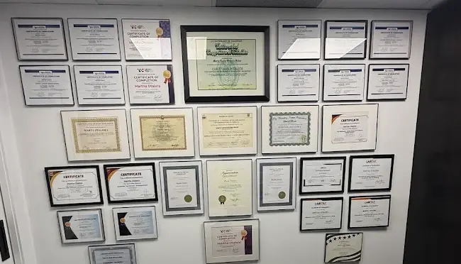Wall of Martha Otalora’s professional certificates in her office